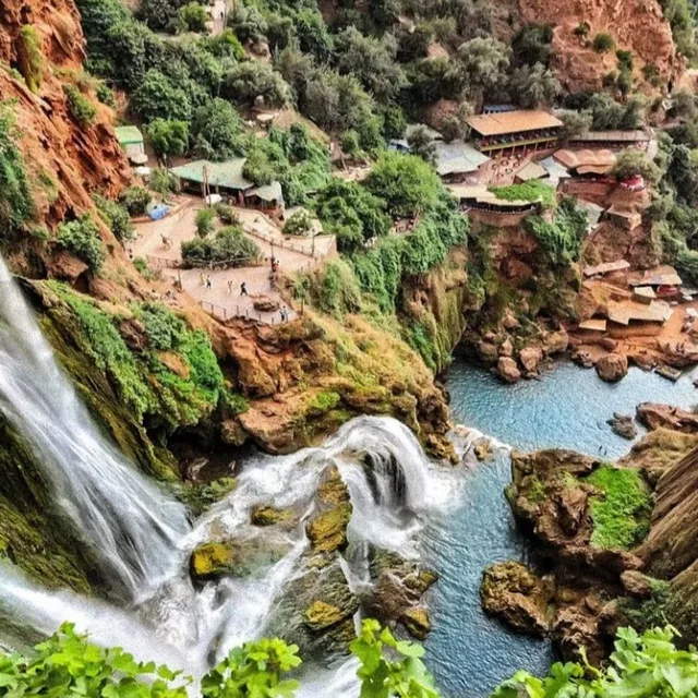 The Ouzoud waterfalls tumbling into a turquoise pool below terraced cafes and red cliffs