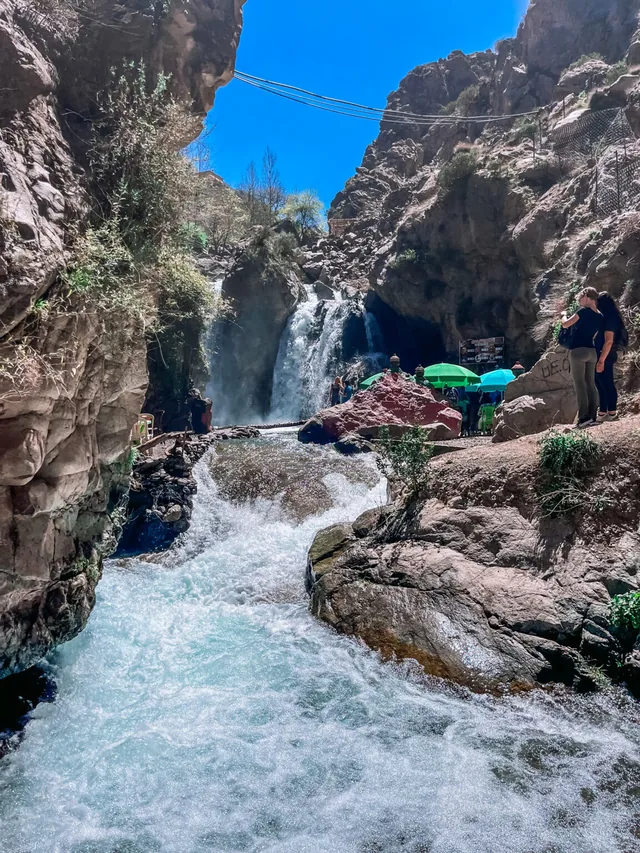 Water tumbling down the Setti Fatma waterfall into a turquoise pool between red gorge walls in the Ourika valley