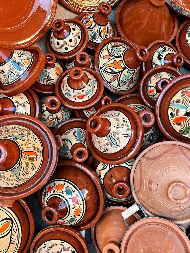Stacks of hand-painted clay tagine pots and lids laid out for sale