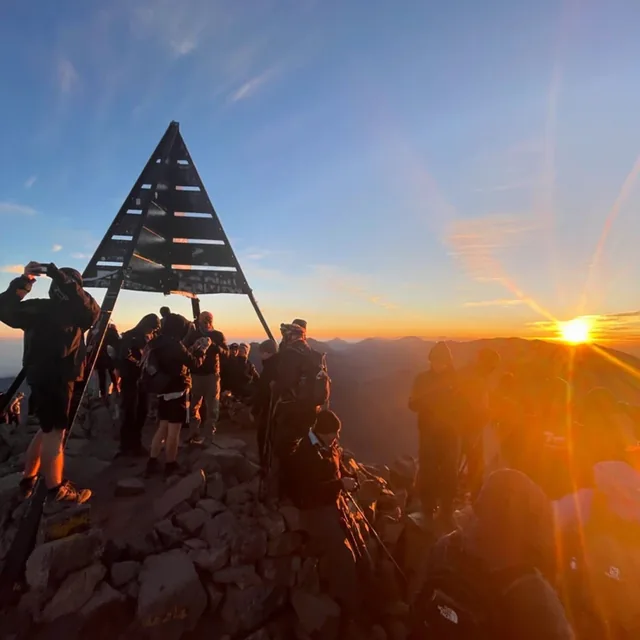 Sunrise breaking over the mountains as trekkers reach the Toubkal summit pyramid