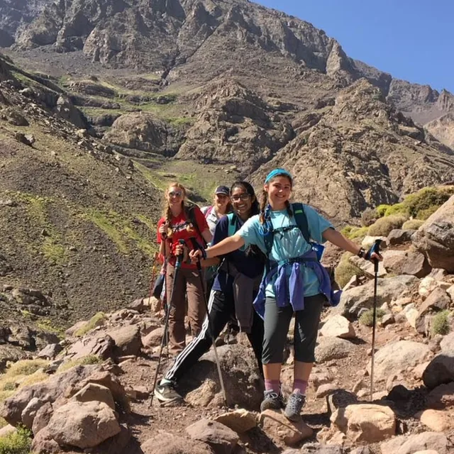 A smiling group of trekkers with walking poles on the Toubkal trail in summer